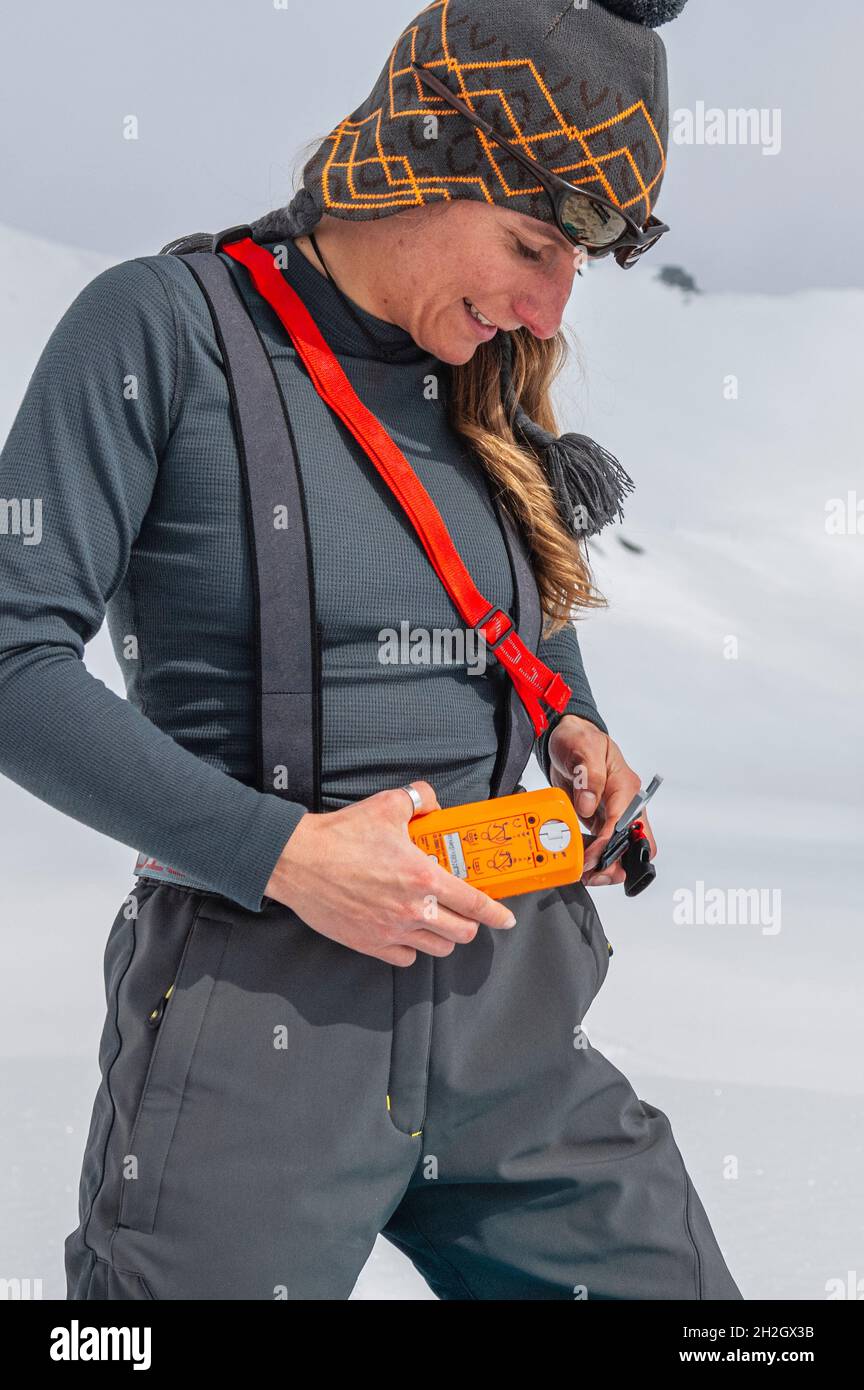 Female alpinist checking avalanche safety equipment Stock Photo