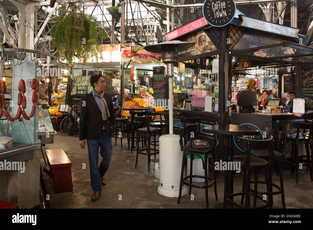 Horizontal shot of an smartly dressed man passing through a coffee shop and some food stalls in San Telmo Market, San Telmo neighborhood, Buenos Aires Stock Photo