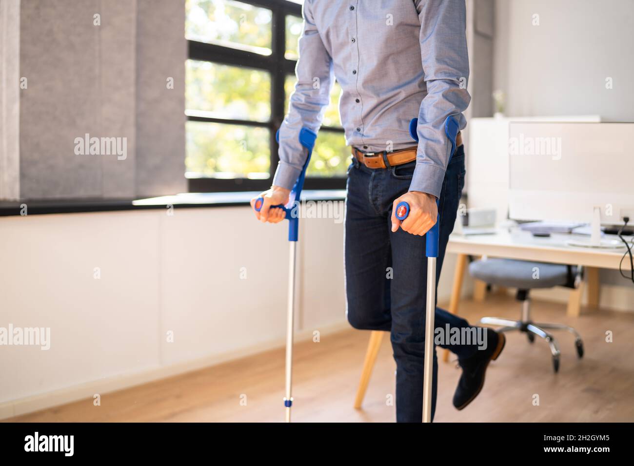 Worker With Crutches At Workplace Or Office. Rehabilitation Benefits