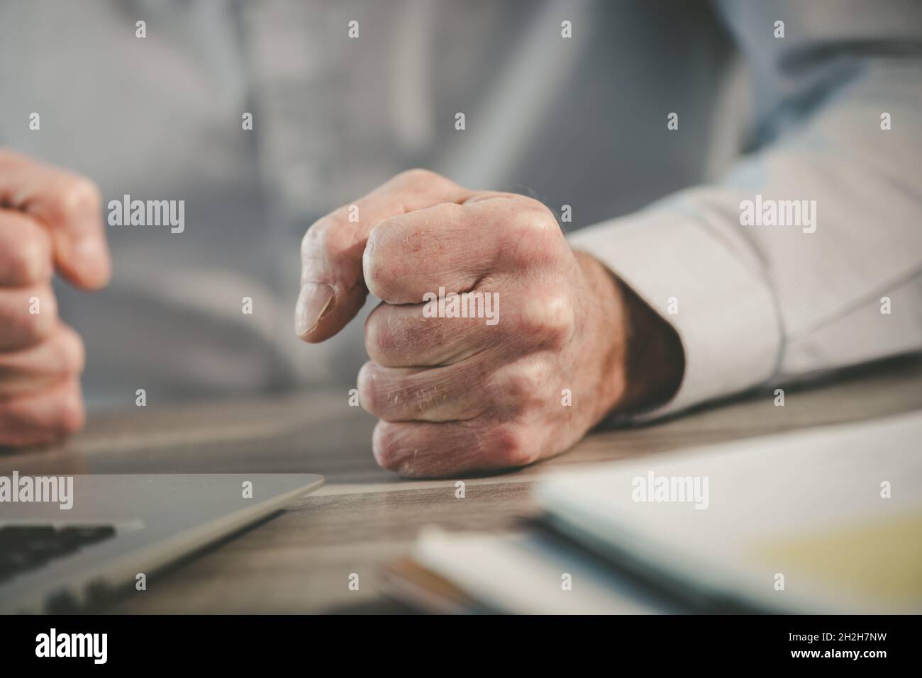Enraged businessman banging his clenched fists on the desk Stock Photo