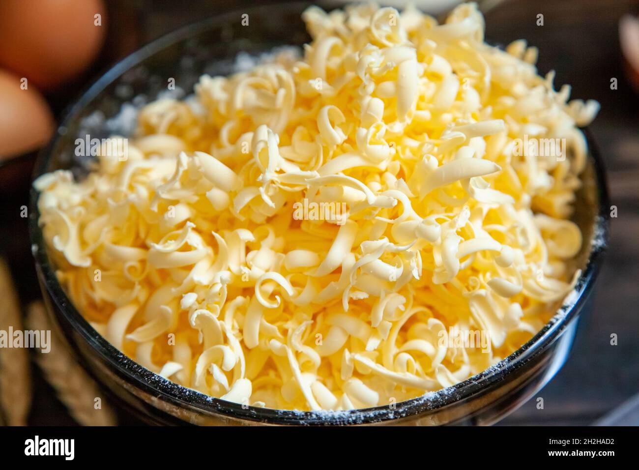 Grated butter for baking on table. Baking ingredients for shortbread pastry: grated butter, flour, eggs, sour cream close up on wooden background. Stock Photo