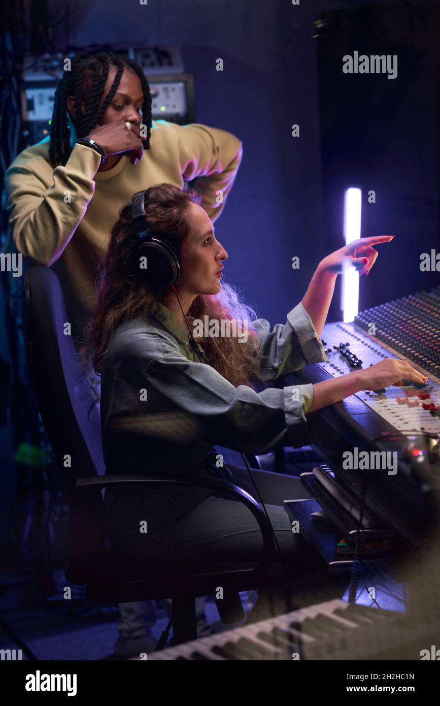 Two musicians writing music in team using music keyboard in the