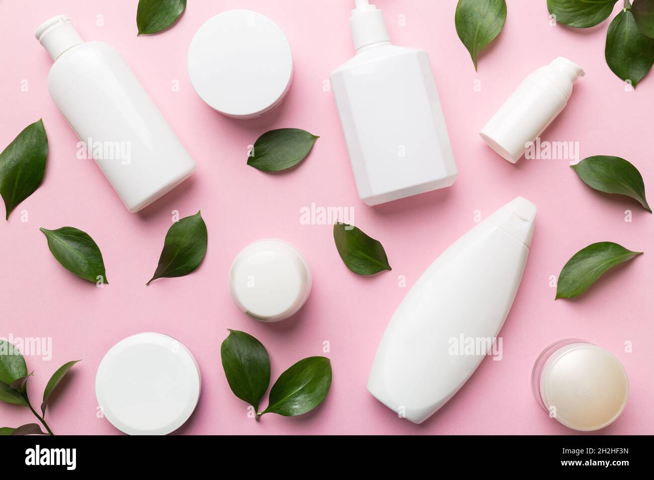 Organic cosmetic products with green leaves on color background. Flat ...