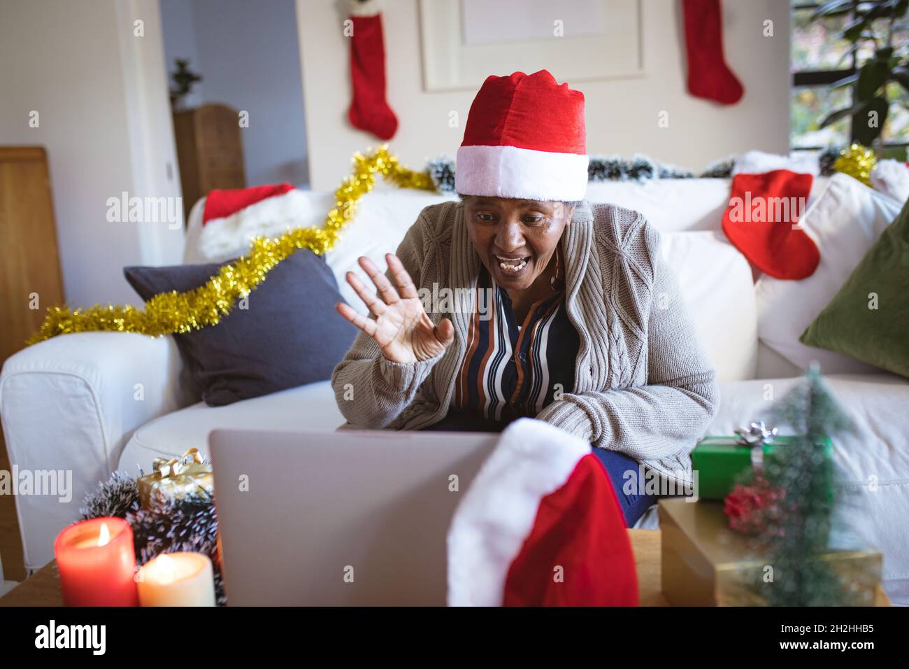 Happy african american senior woman in santa hat making laptop christmas video call Stock Photo
