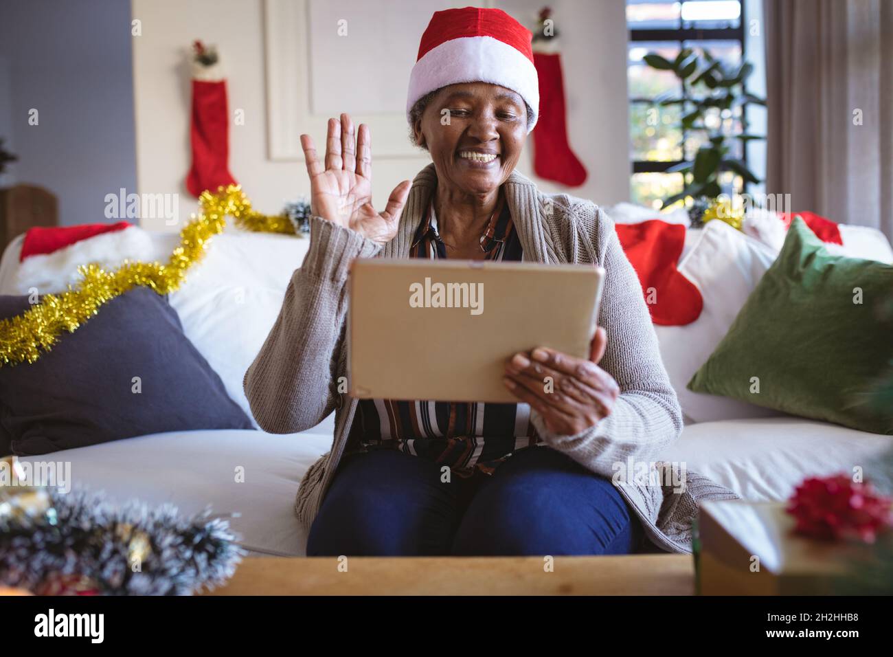 Happy african american senior woman in santa hat making tablet christmas video call Stock Photo