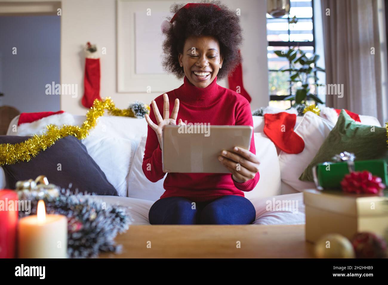 Happy african american woman in santa hat making tablet christmas video call Stock Photo