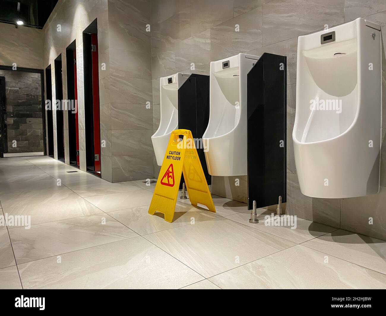 Wet floor sign near urinals area in public toilet during cleaning