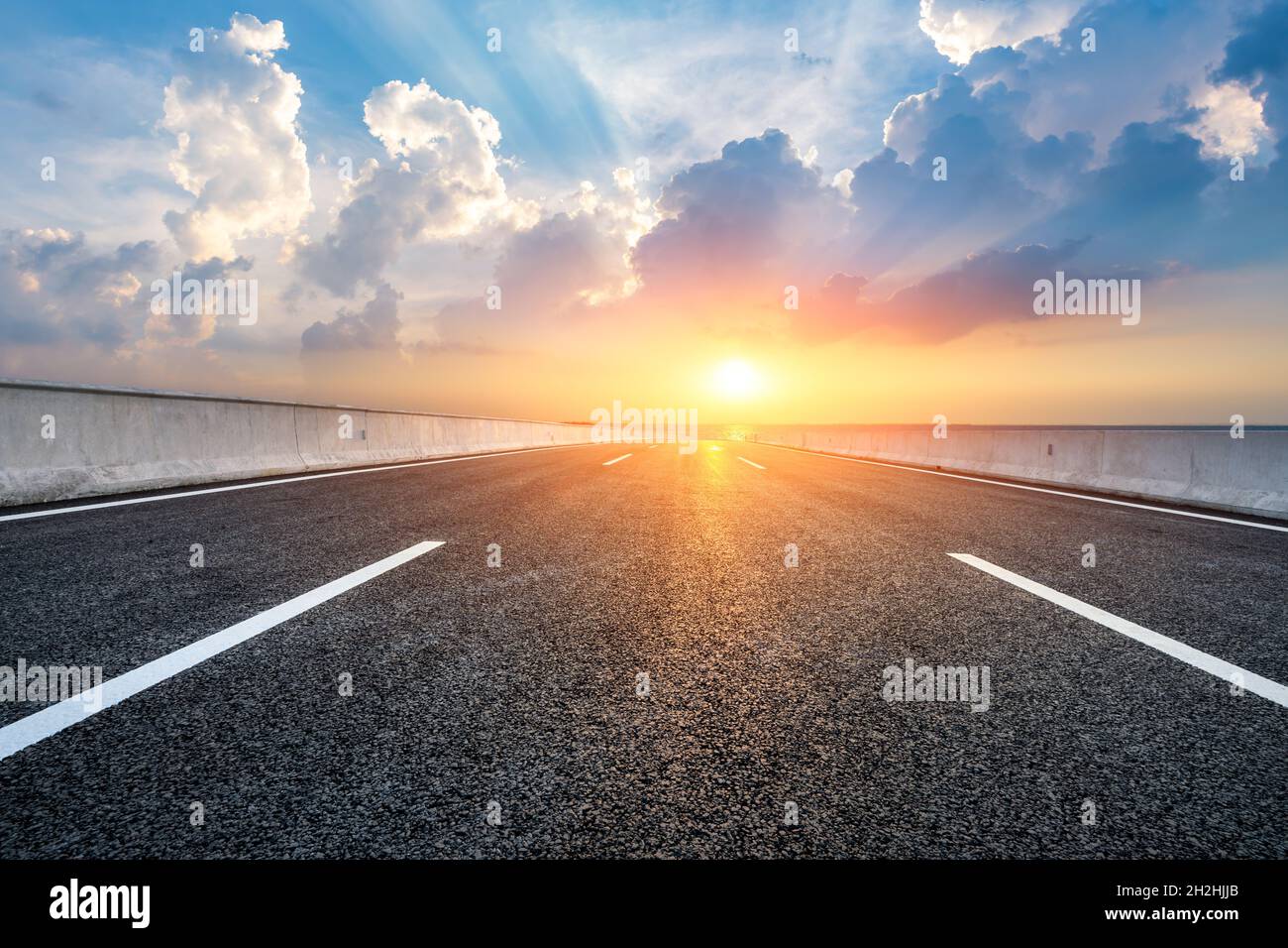Asphalt road and lake with beautiful clouds at sunset Stock Photo - Alamy