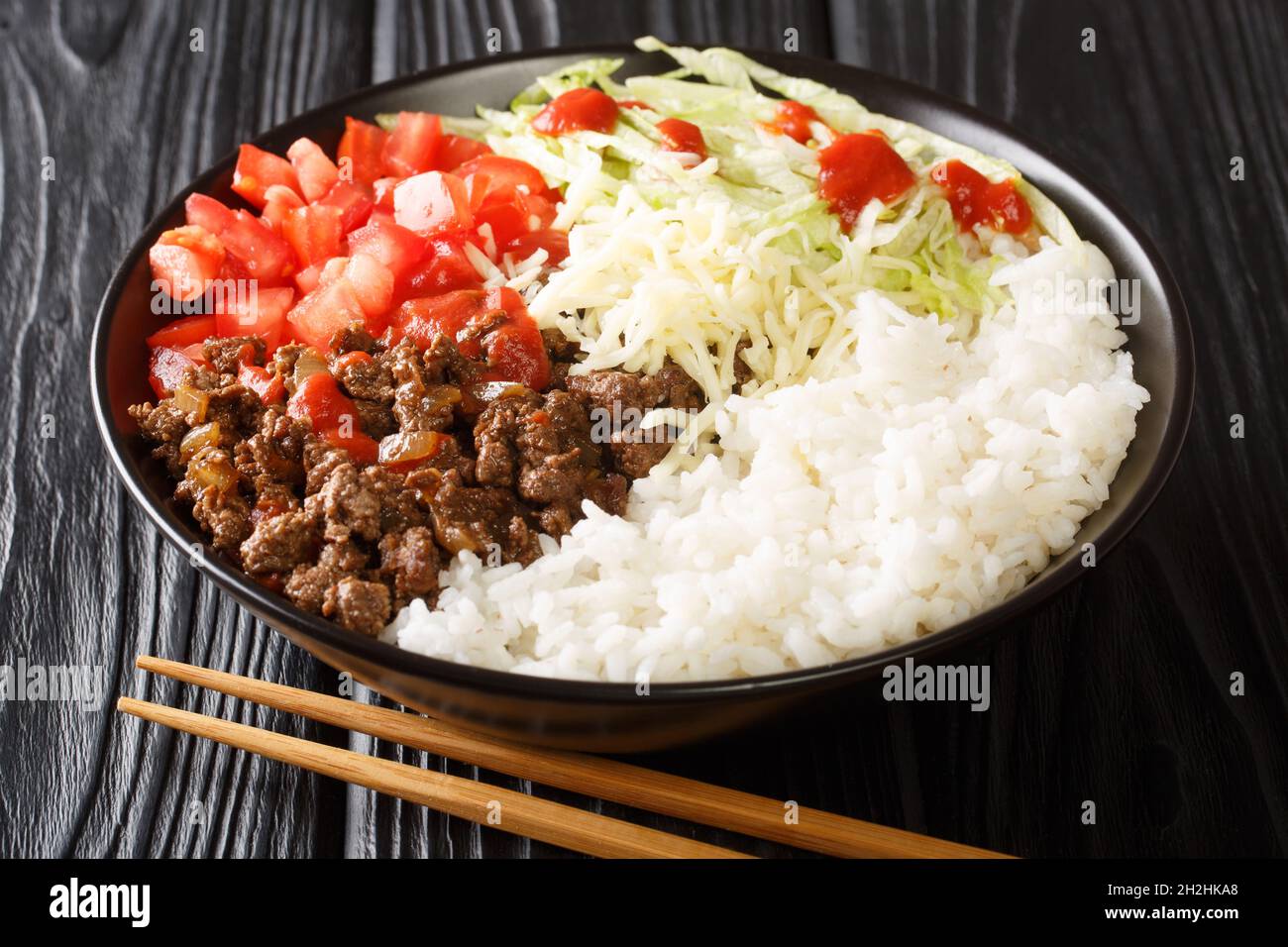 Japanese taco rice with ground beef, vegetables, cheese and sauce close