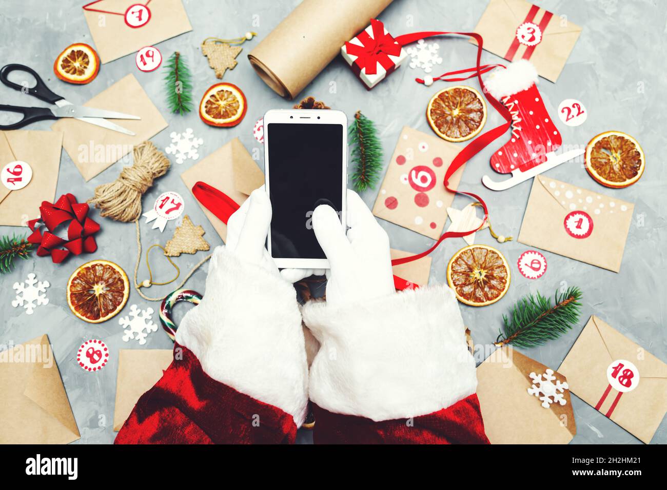 Hands of Santa Claus with a phone. Preparing the Advent Calendar.  Seasonal Christmas tradition. Flat lay, top view. Stock Photo