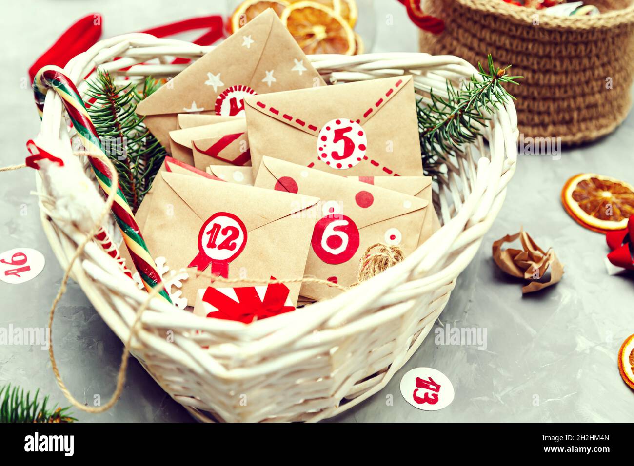 Advent calendar waiting for Christmas. Collection of small envelopes in  basket with numbers and tasks for children. Seasonal Christmas tradition. Stock Photo