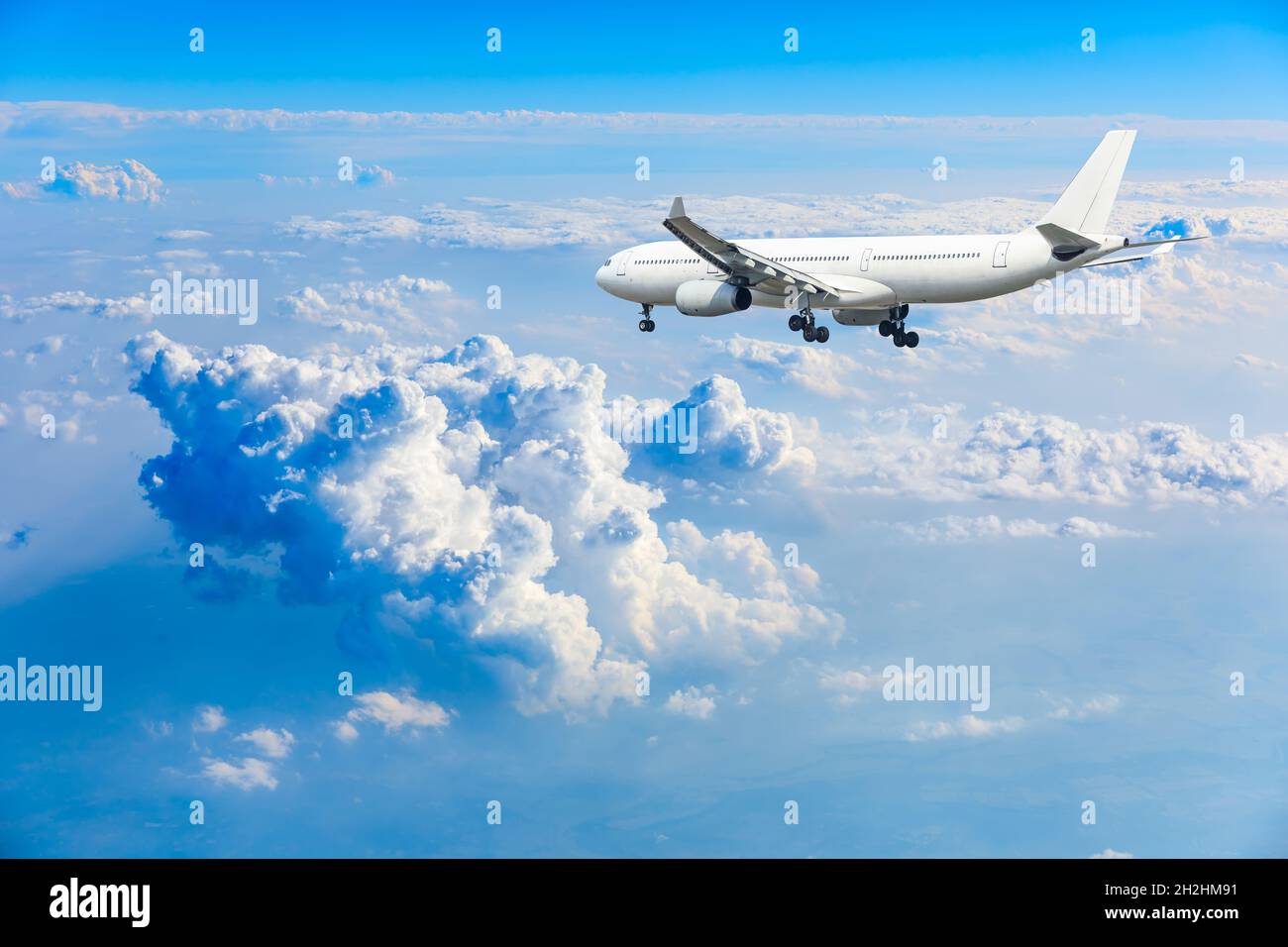 Commercial airplane flying above blue sky and white clouds Stock Photo ...