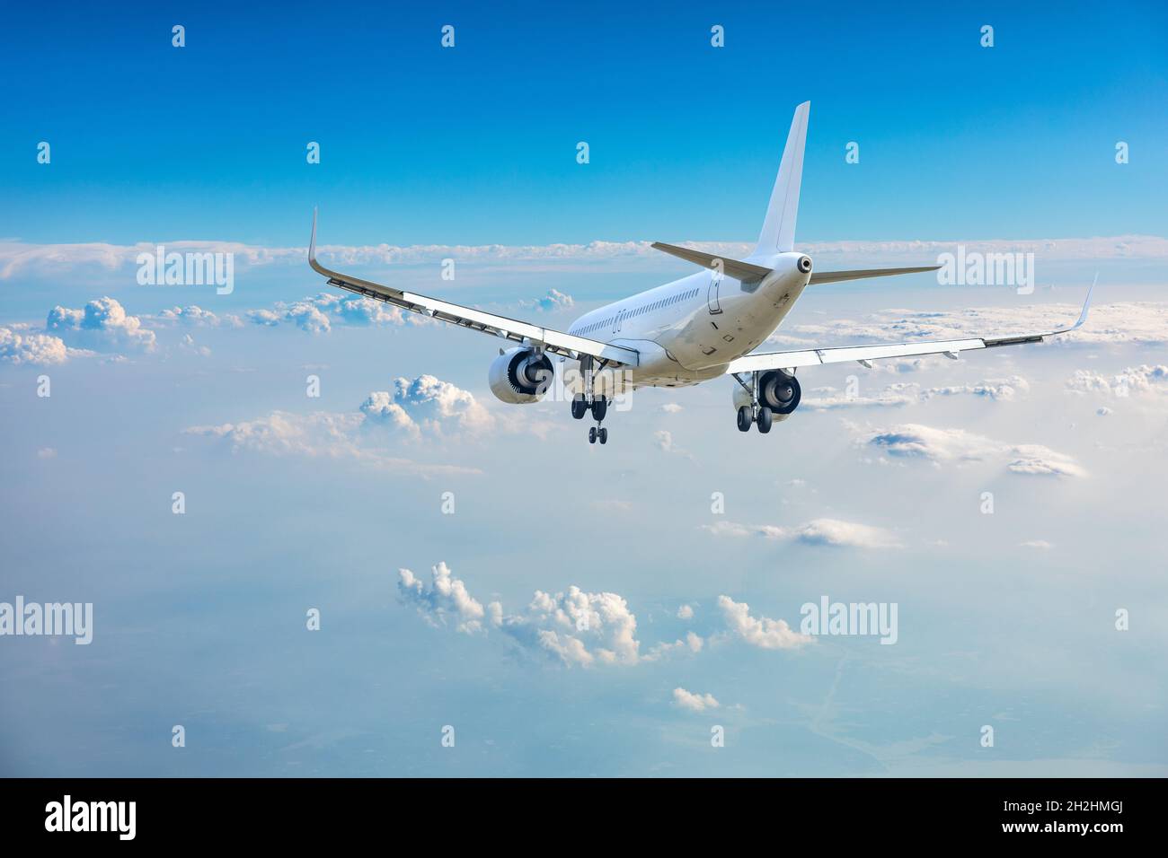 Commercial airplane flying above blue sky and white clouds Stock Photo ...