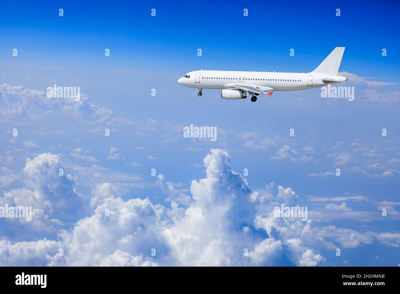 Commercial airplane flying above blue sky and white clouds Stock Photo ...