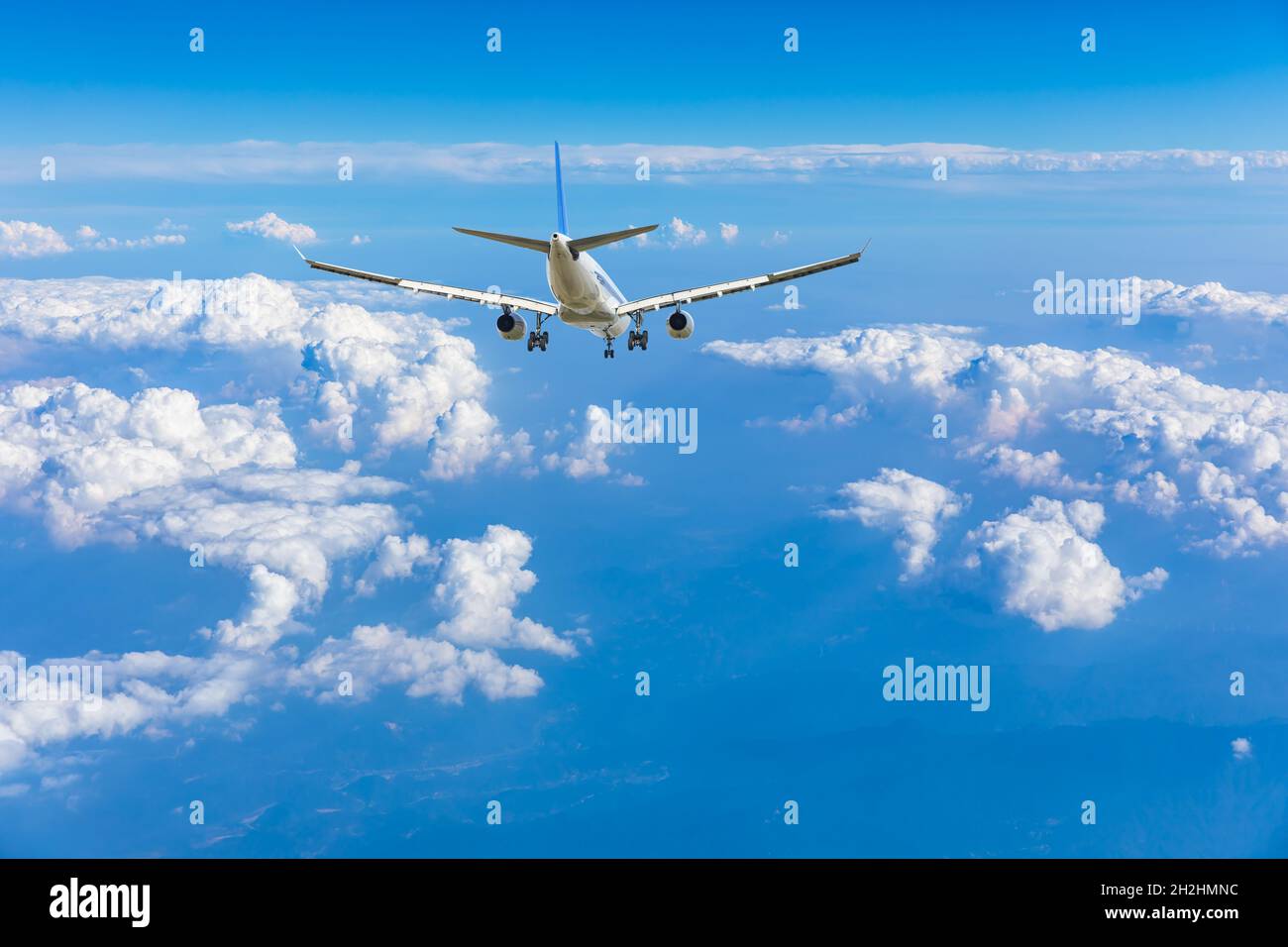 Commercial airplane flying above blue sky and white clouds Stock Photo ...
