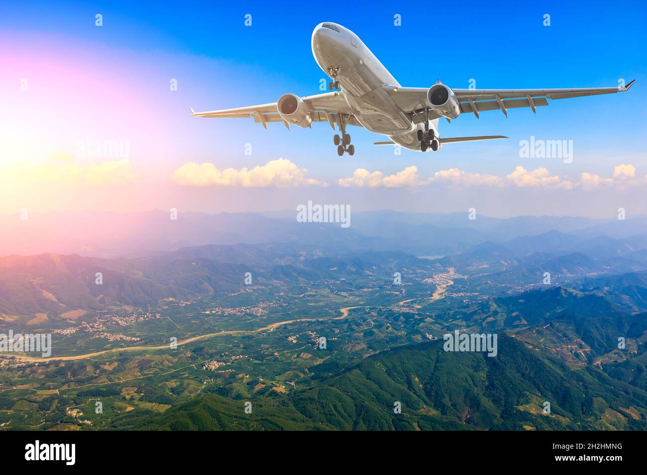 Commercial airplane flying above blue sky and white clouds. Stock Photo