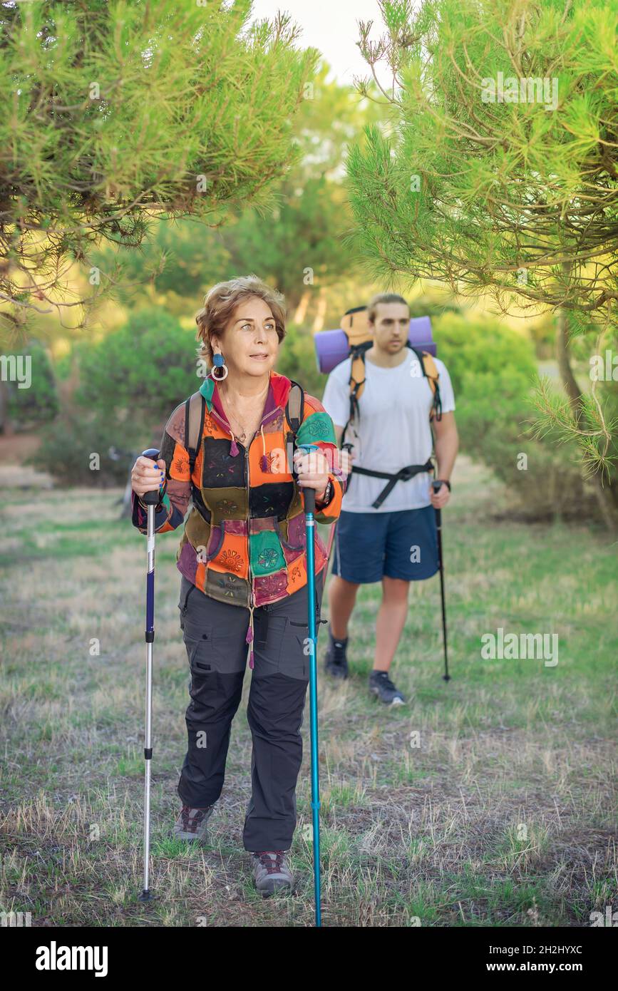 Older lady hiker in the foreground walking in the countryside with a young hiker. Elderly sportswoman Stock Photo