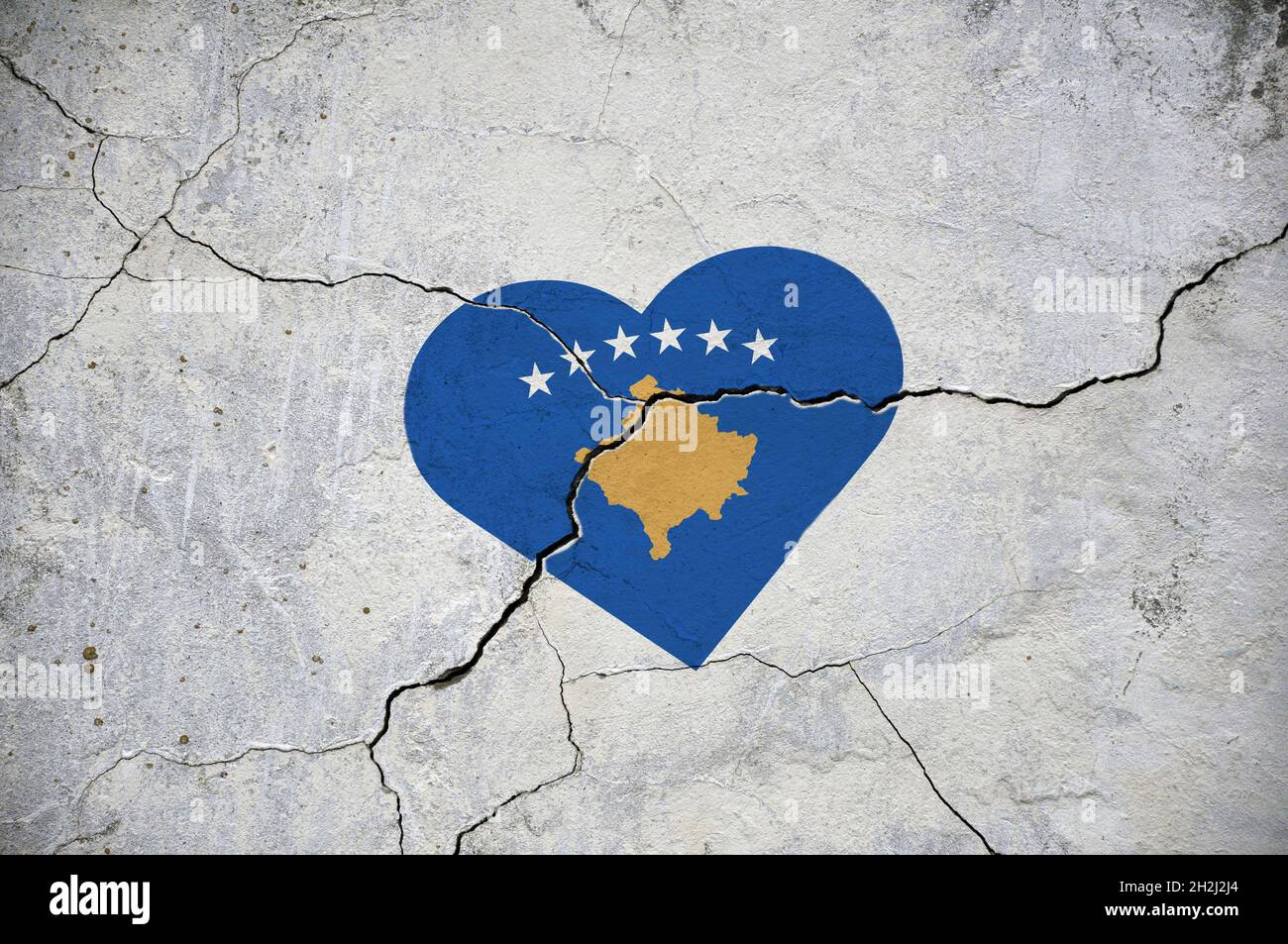 The flag of Republika Kosovo symbolizes a heart on a cracked concrete wall. Stock Photo