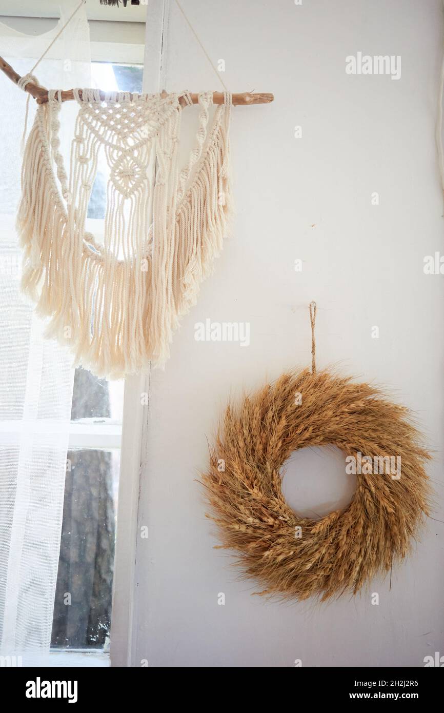 Decoration of the wall in the village house macramé and a wreath of cereals. Interior in boho style Stock Photo