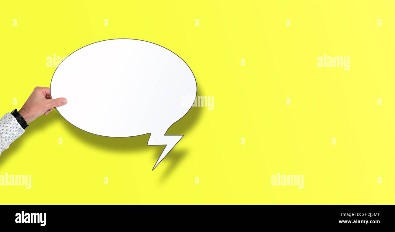 hand holding empty speech bubble against yellow background with copy space Stock Photo