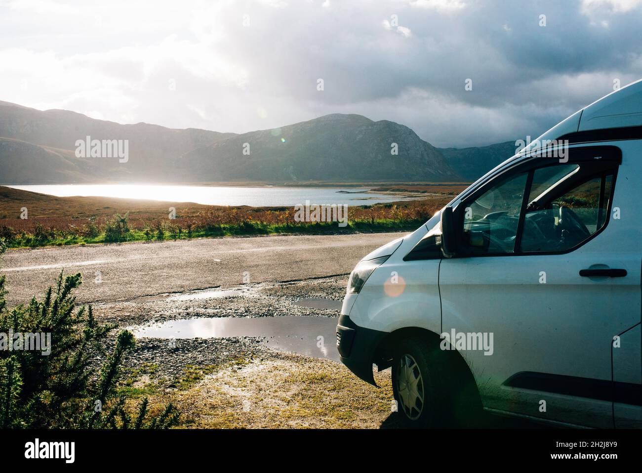 a campervan parked up wild camping on the NC500 road trip in scotland. Scenic view of lake and mountains Stock Photo