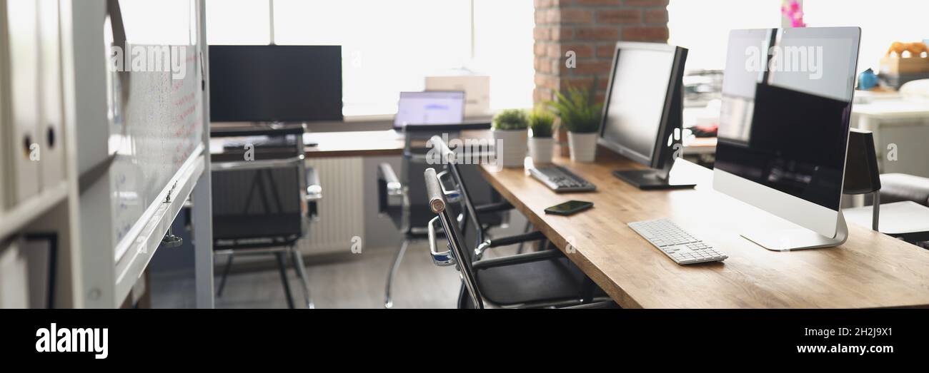 Computer monitors standing on table in empty office Stock Photo