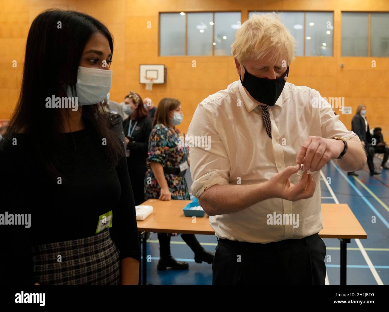 Prime Minister Boris Johnson shakes a dose of the pfizer vaccine as it is diluted before being administered, during a visit to the Covid-19 vaccine centre at the Little Venice Sports Centre in west London. Picture date: Friday October 22, 2021. Stock Photo