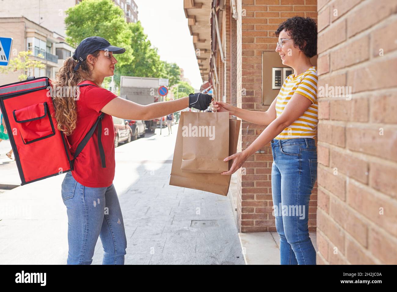 A delivery girl delivers bags of food on the street Stock Photo