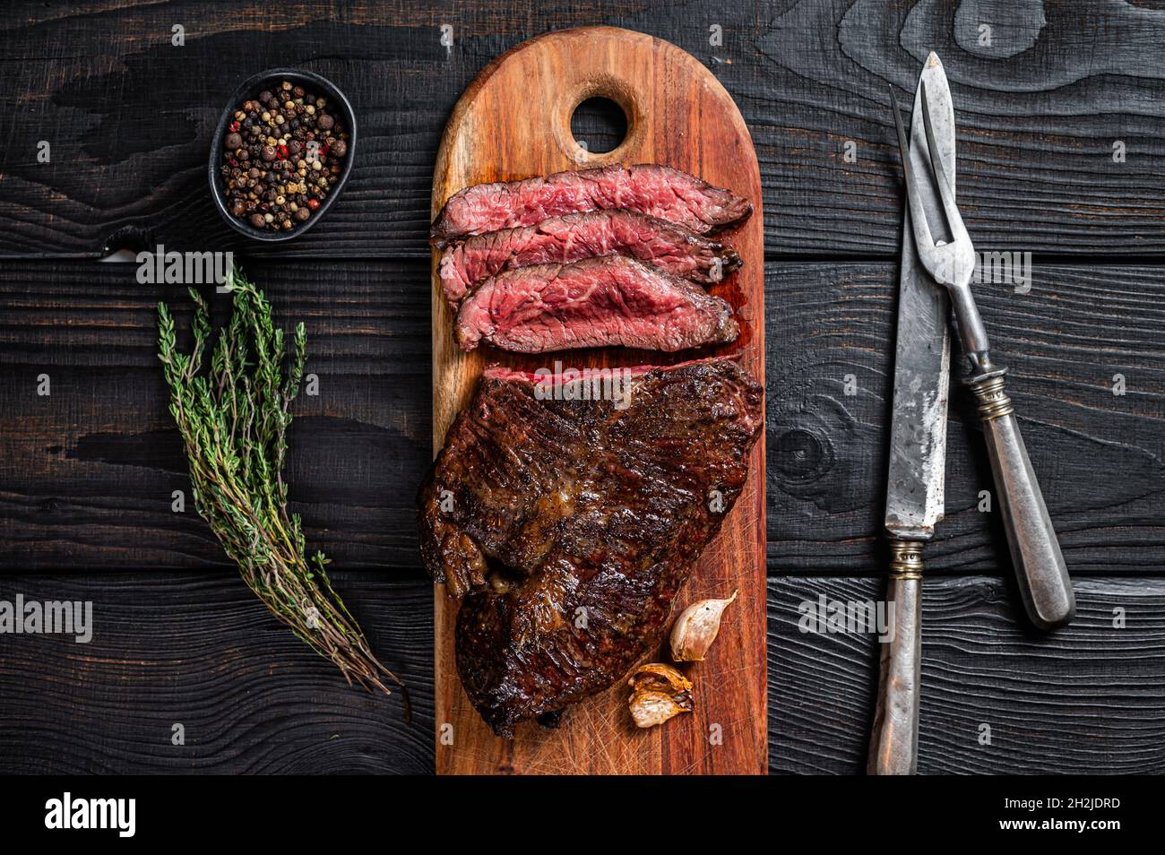 Grilled Butchers choice steak Onglet Hanging Tender beef meat on a cutting board. Black wooden background. Top View Stock Photo