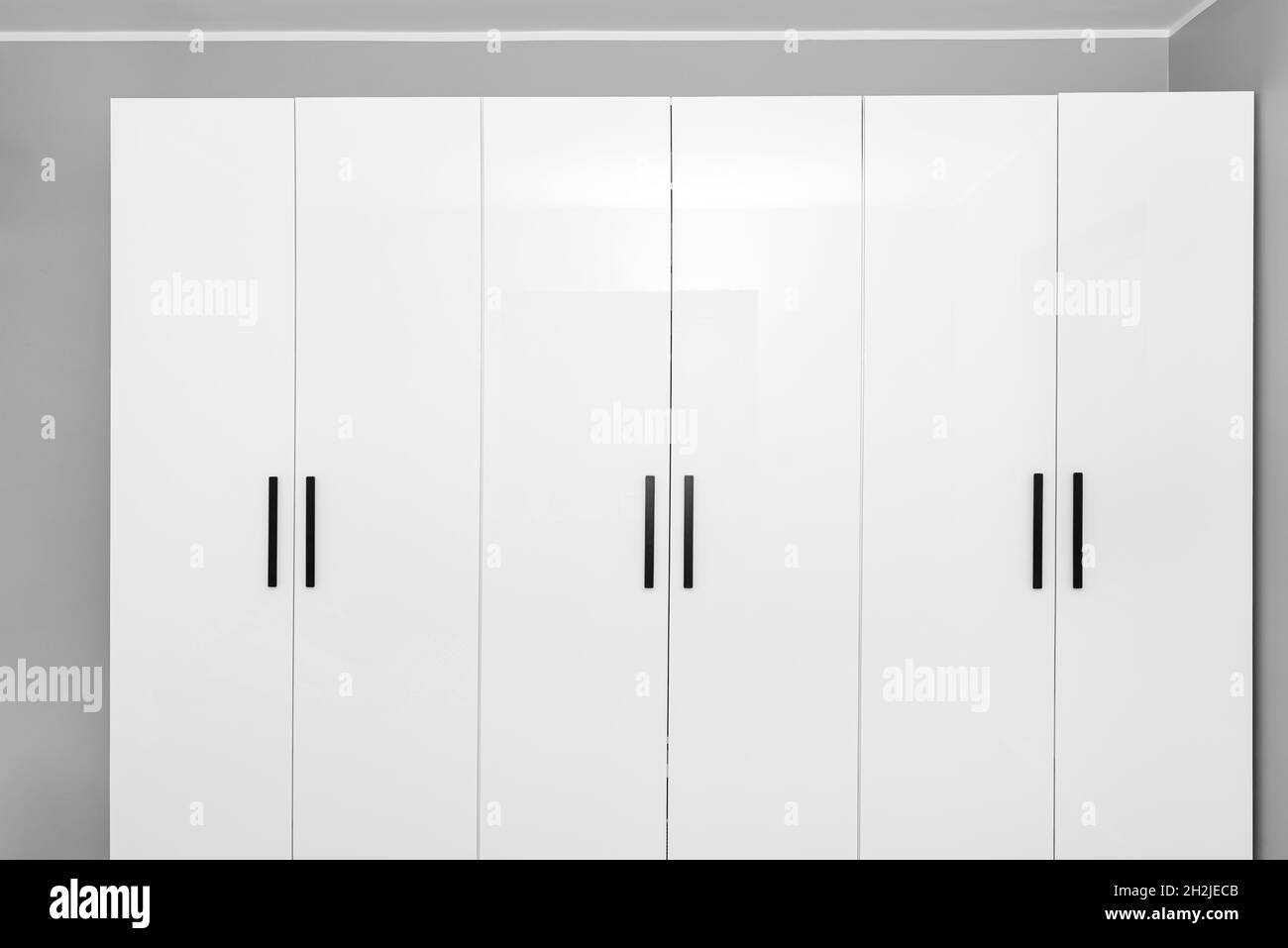 Large and high wardrobe in the bedroom with white fronts and black handles Stock Photo Alamy