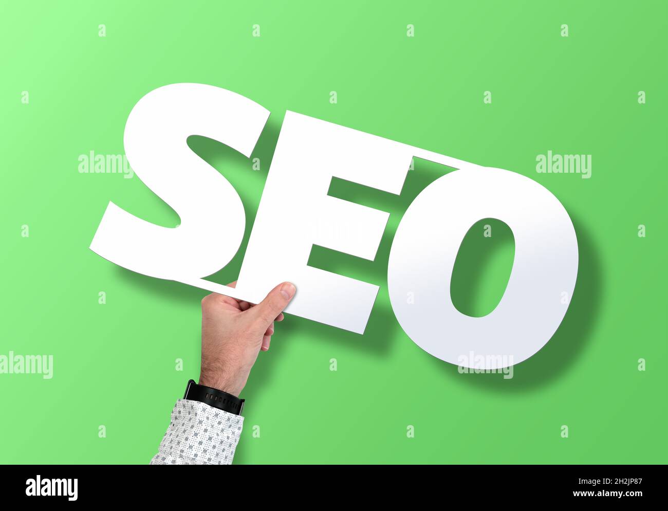 hand holding SEO sign against green background, search engine optimization concept Stock Photo