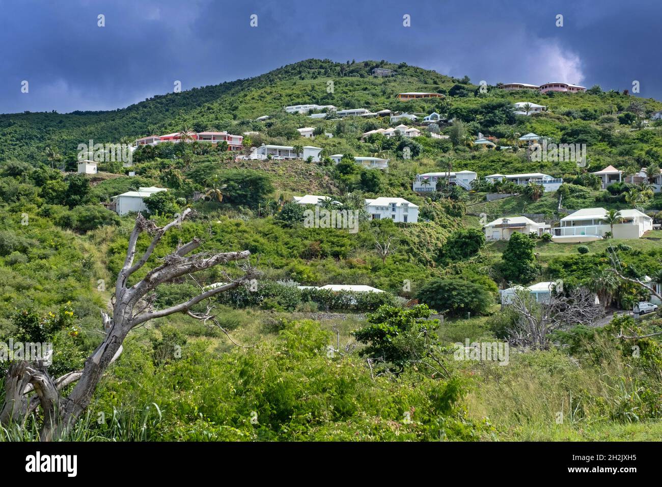 Threatening dark rain cloud over houses on hillside on the east side of the Dutch island part of Sint Maarten in the Caribbean Sea Stock Photo