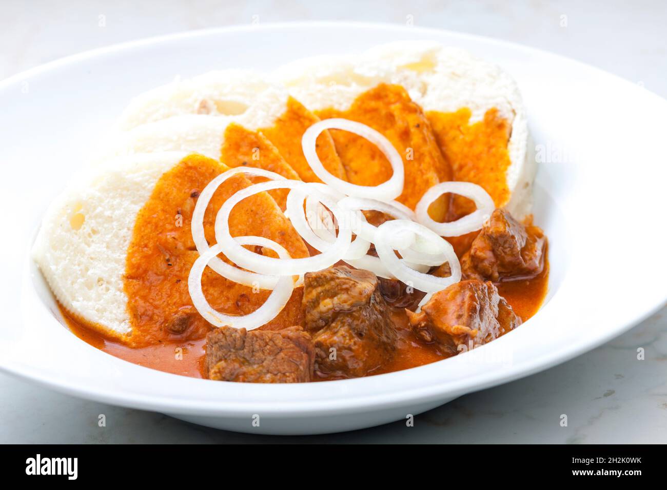 beef goulash with dumplings and rings of white onion Stock Photo