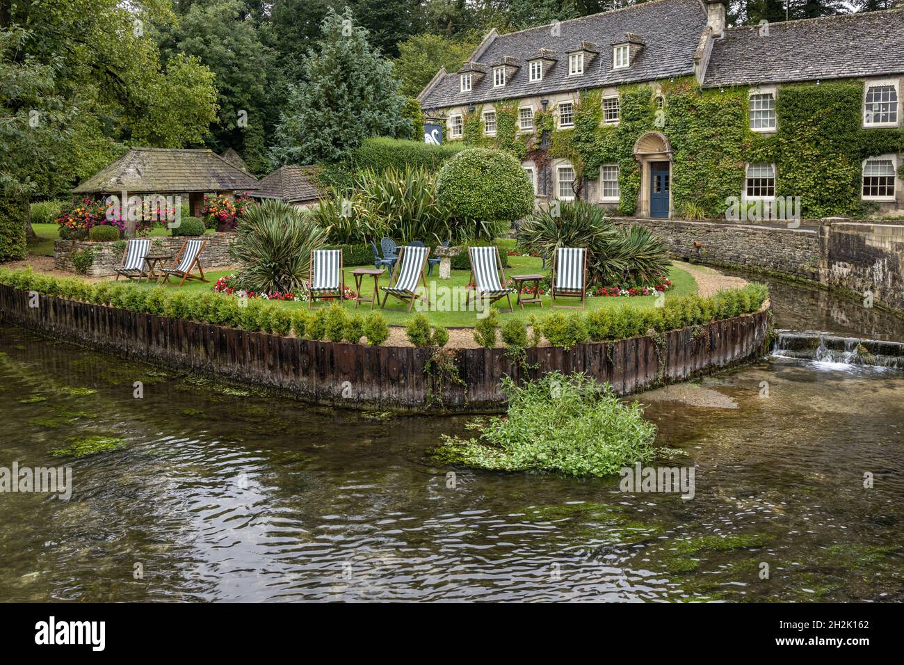 The pretty landscaped garden of the ivy covered Swan Hotel in the picturesque village of Bibury in the Gloucestershire Cotswolds, England. Stock Photo