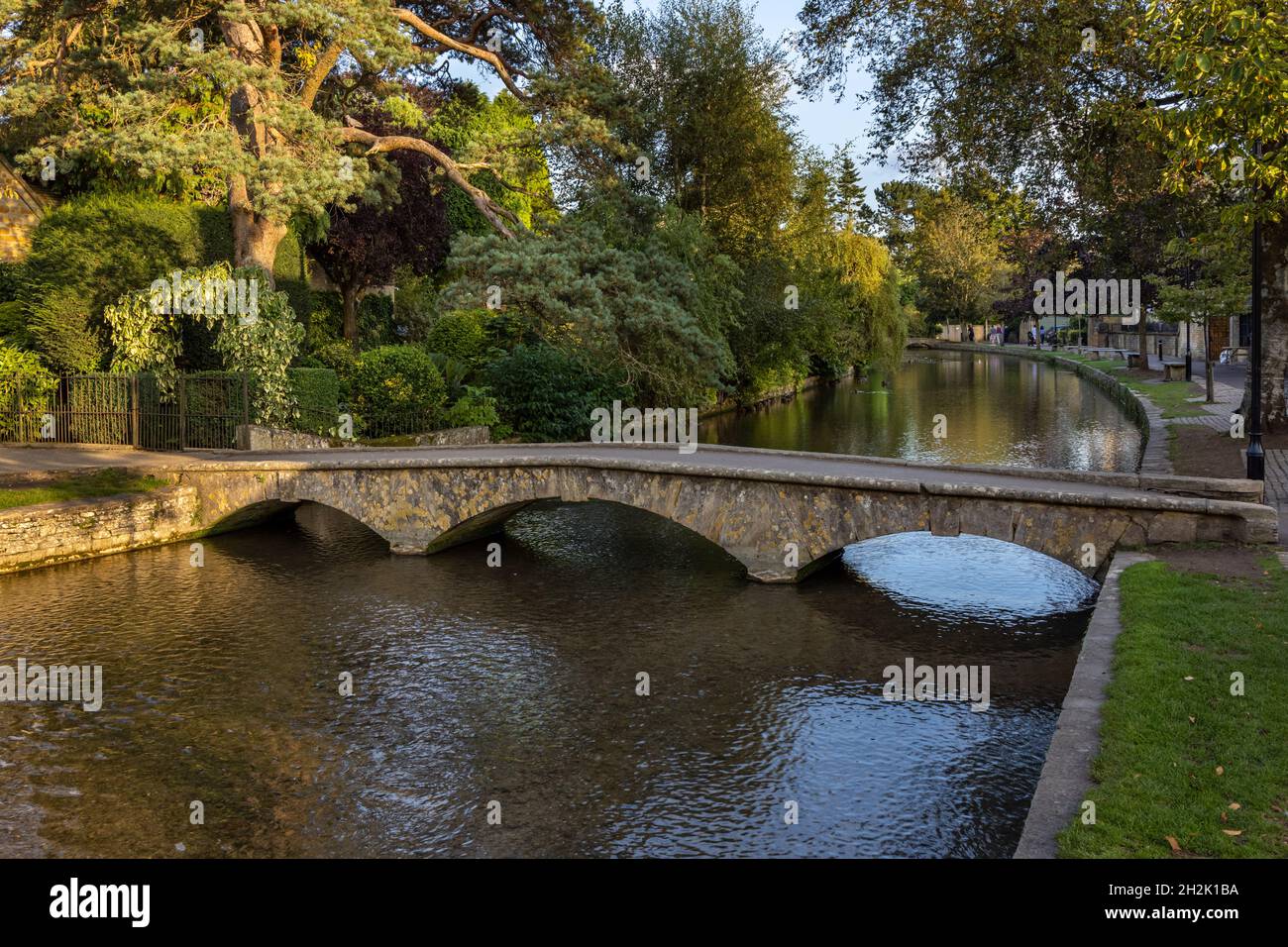 An arched stone bridge crossing the River Windrush in the picturesque Cotswolds Village of Bourton-on-the-Water, Gloucestershire, England. Stock Photo