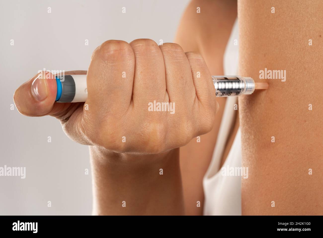 closeup of injecting an insulin injection in hand on a gray background Stock Photo
