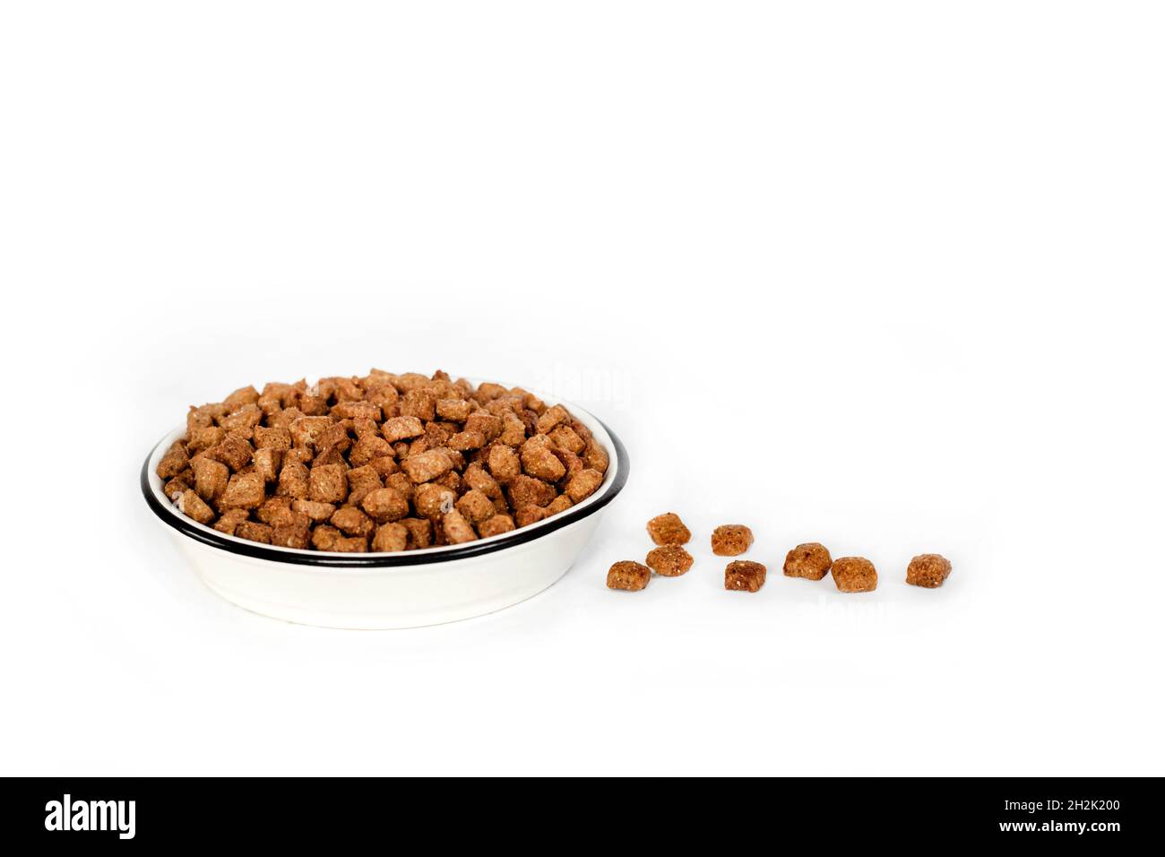 Dry pet food in a white ceramic bowl isolated on white background. Copy space Stock Photo