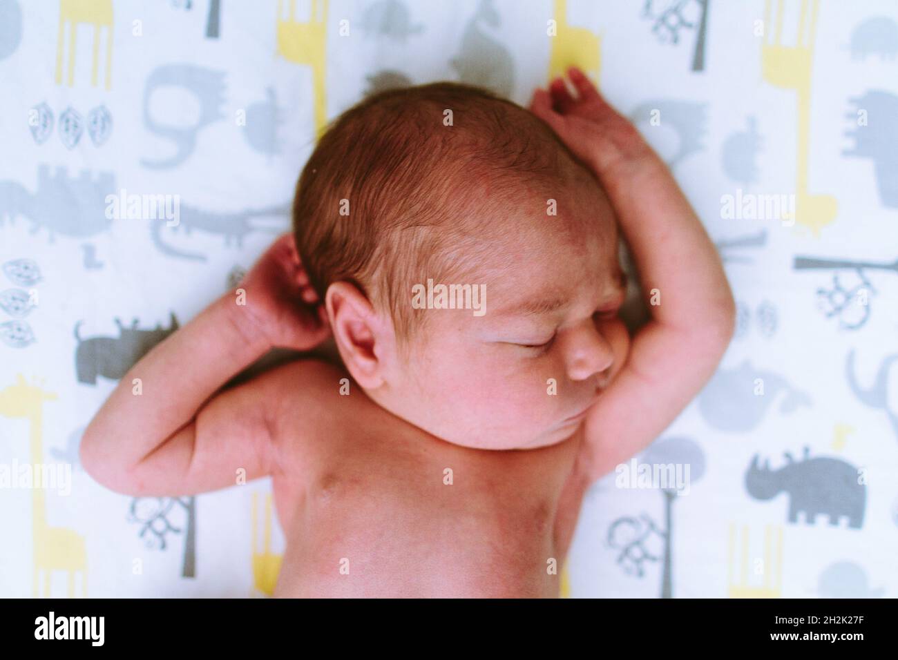 Above view of a baby boy sleeping with his arms above his head Stock