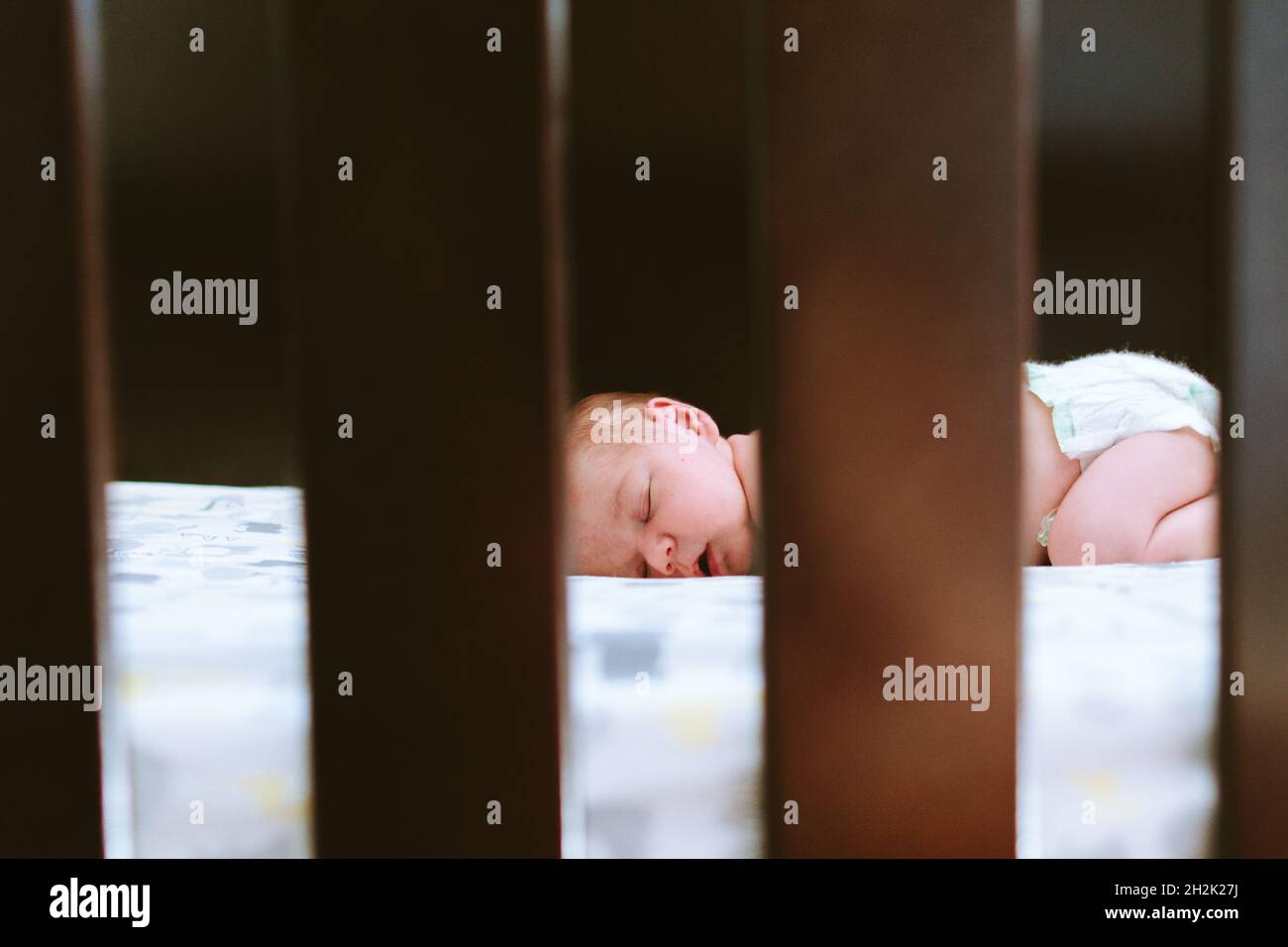 View through the crib slats of a baby boy sleeping Stock Photo Alamy