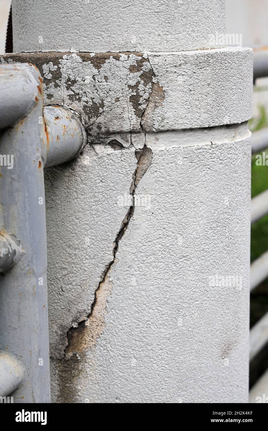 Cracked grey concrete surface with visible reinforcement, Rust in reinforcement of Concrete fence, Broken or weak concrete. Stock Photo