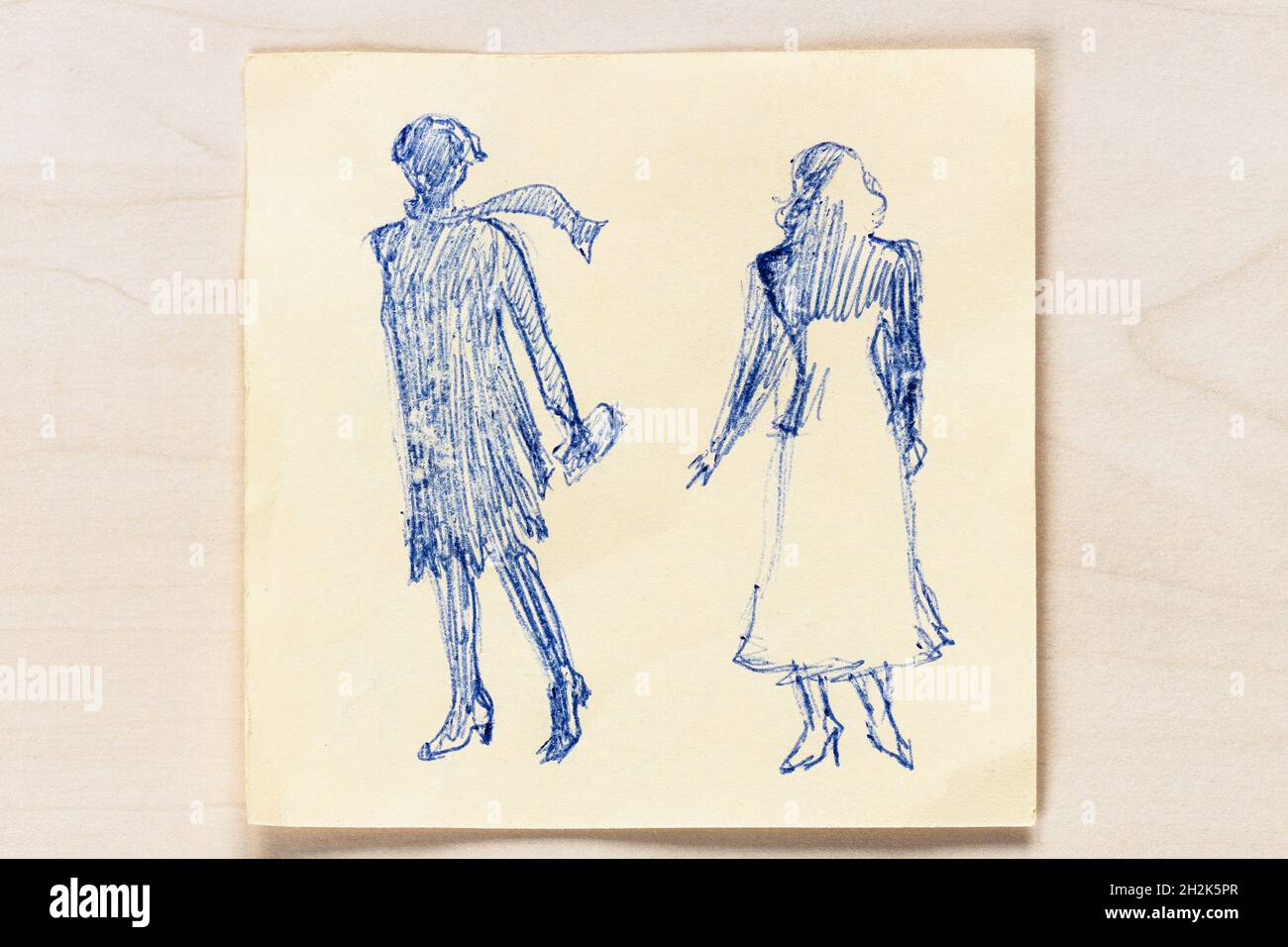 sketch of fashionable silhouette of women of the 20s and the 30s of the XX century hand drawn with blue ball pen on note paper on light brown table Stock Photo
