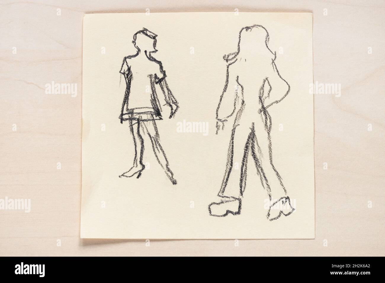 sketch of fashionable silhouette of women of the 60s and the 70s of the XX century hand drawn with black graphite pencil on note paper on light brown Stock Photo
