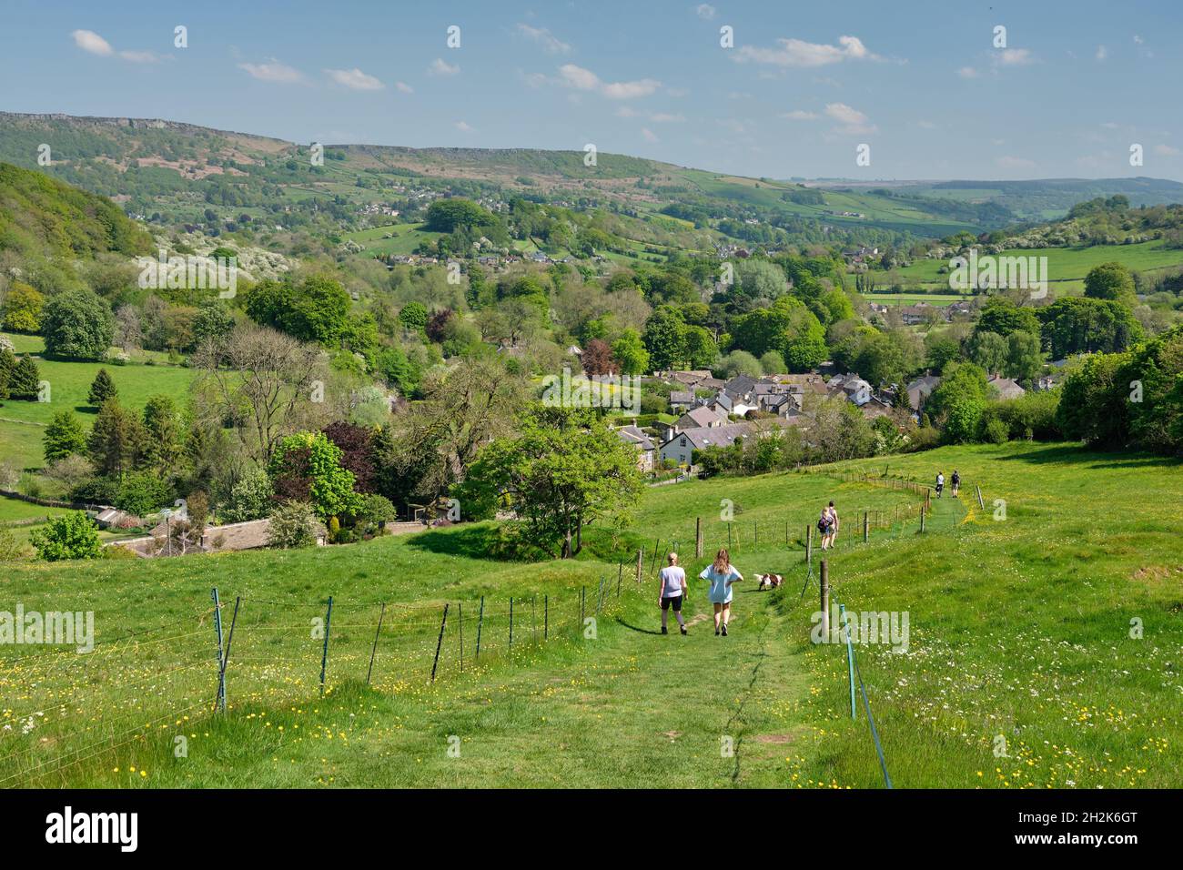 Walkers descendng grassy path to Stoney Middleton, Hope Valley, Peak District, UK Stock Photo