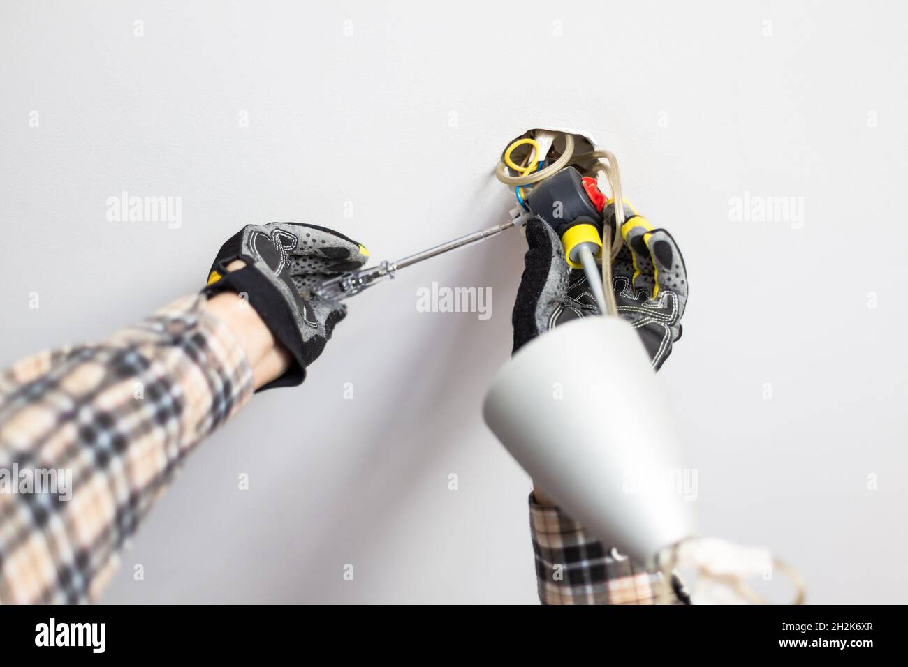 electrician repairing electrical connection of ceiling lamp at home ...