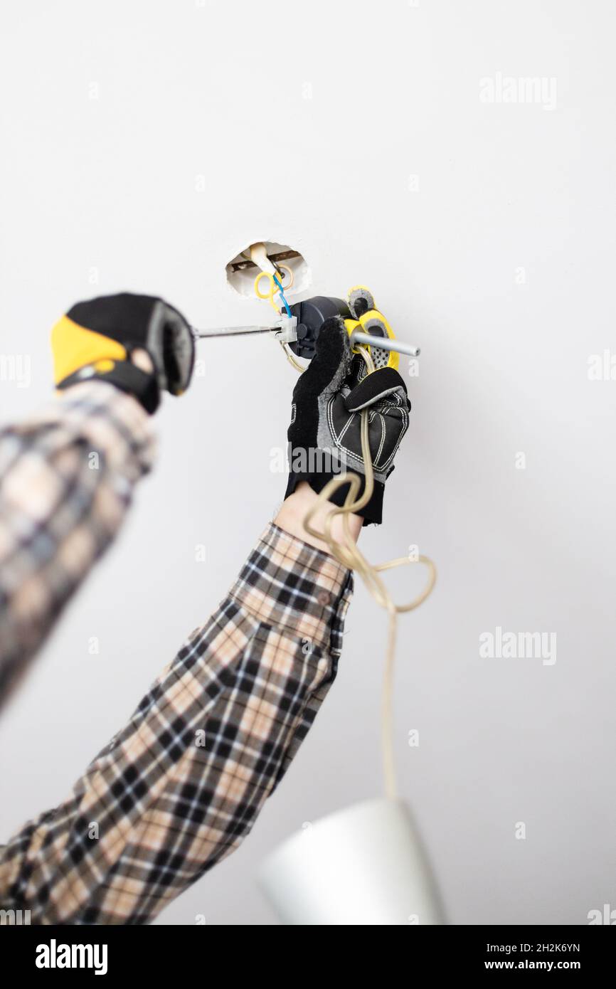 electrician fixes electrical wiring of ceiling lamp at home Stock Photo