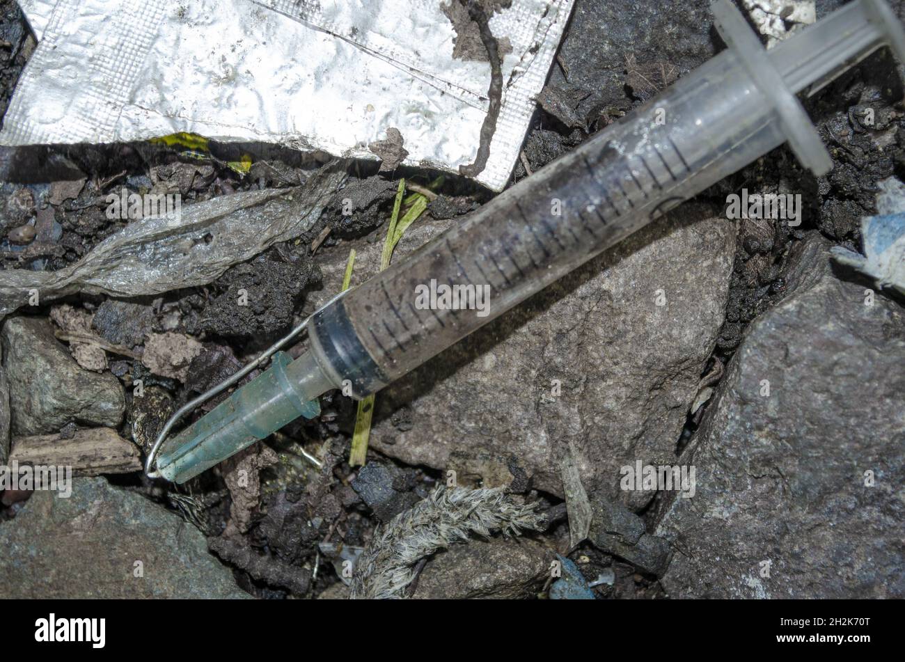 Closeup shot of a drug user's syringe and tackle on waste ground in the inner-city area. Stock Photo
