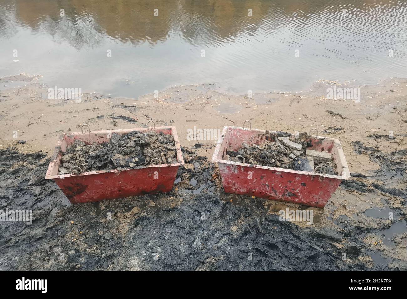 Two boxes with garbage from the bottom of the river on the river bank. Stock Photo