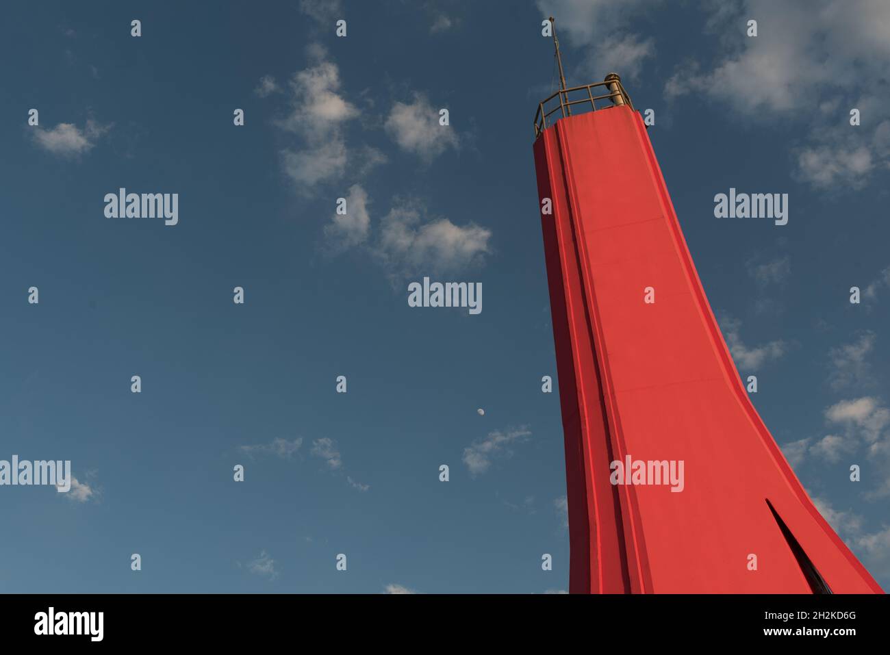 Low angle shot of a red lighthouse under a blue sky with tiny clouds ...