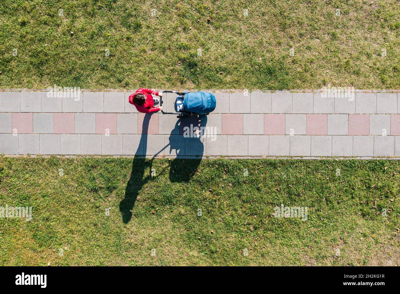 Aerial view of parent with a stroller on a walk during sunny day, perspective directly above Stock Photo