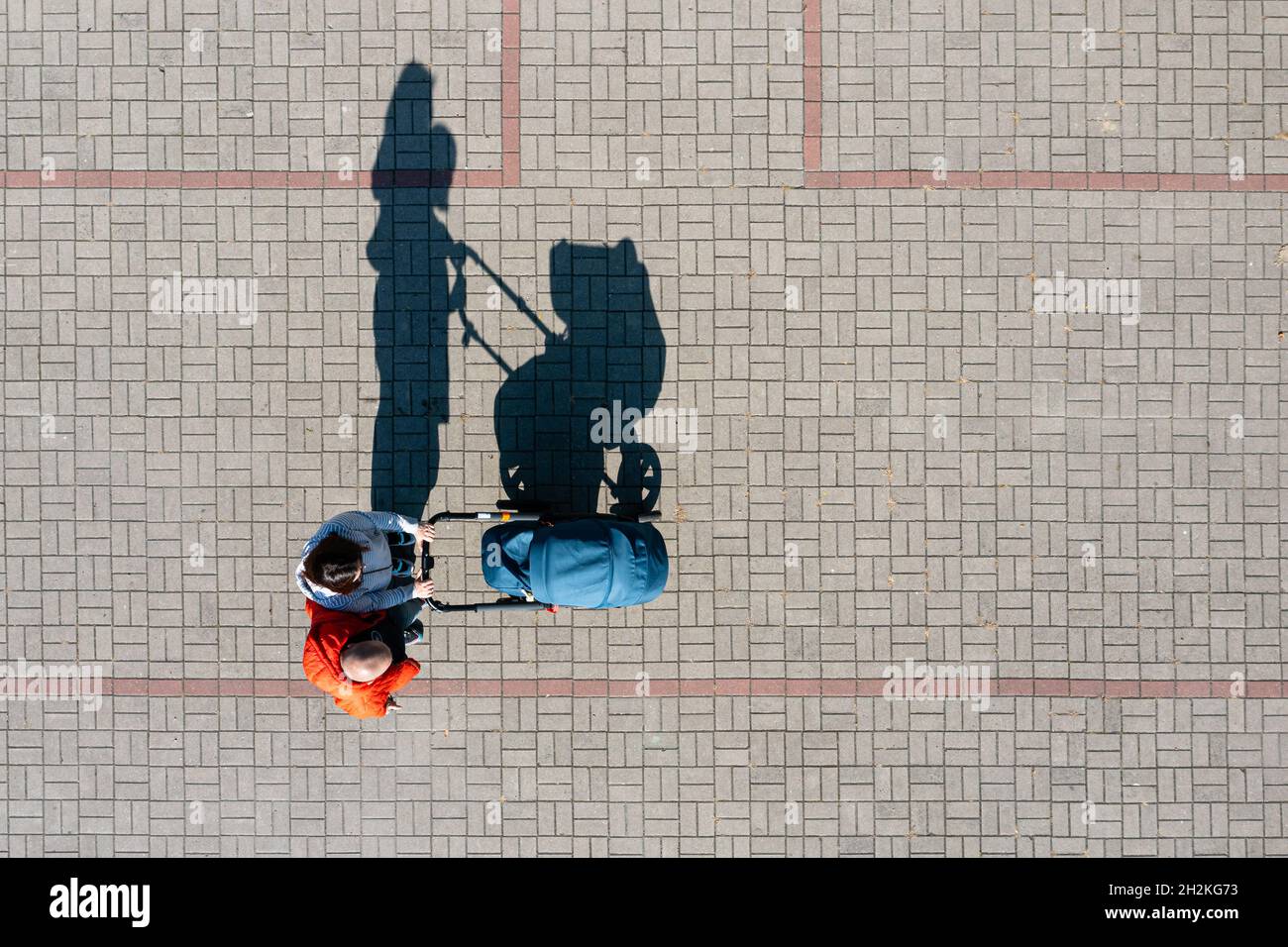 Aerial view of parent with a stroller on a walk during sunny day, perspective directly above Stock Photo